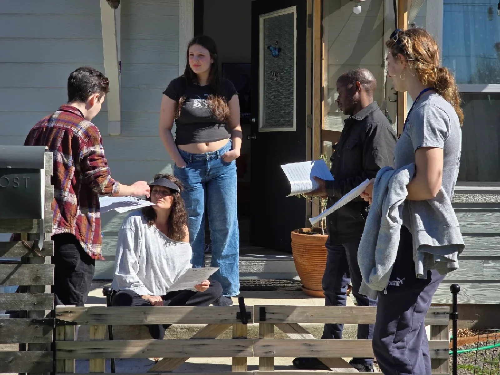 A team of three volunteers speak with two women who are outside their home on the porch.