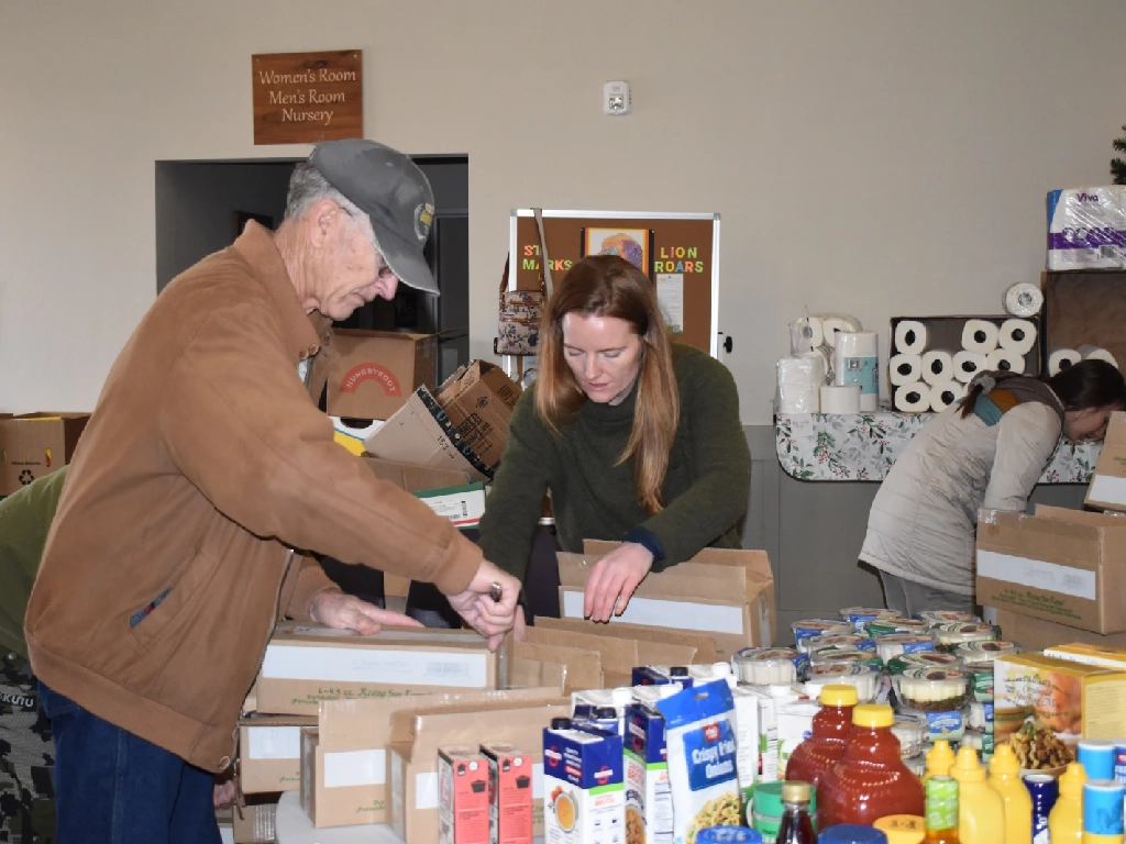 Two people work together to bag of non-perishable food for distribution