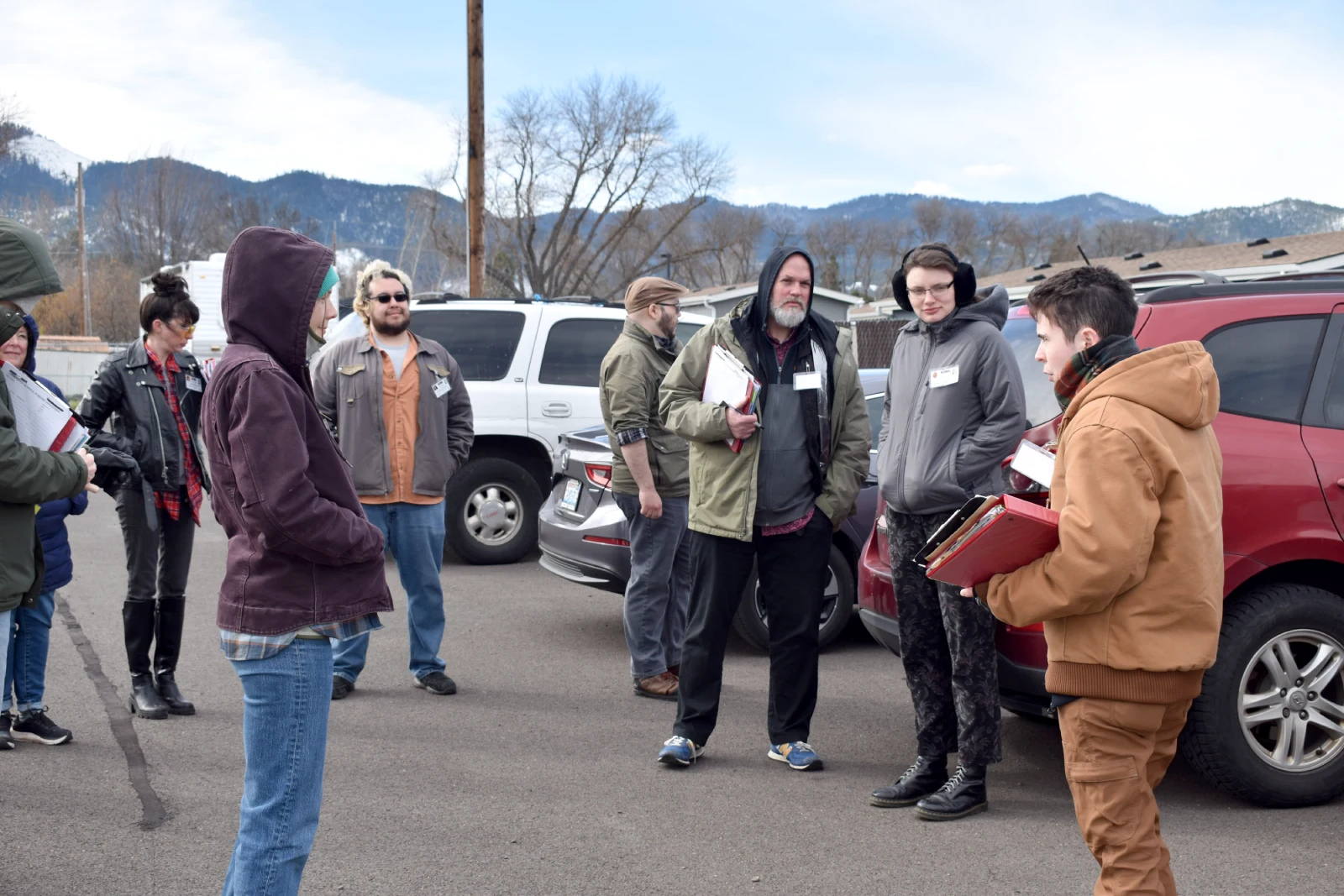 A group of eight people gather around in a circle to listen to a briefing from an organizer about the day's activity