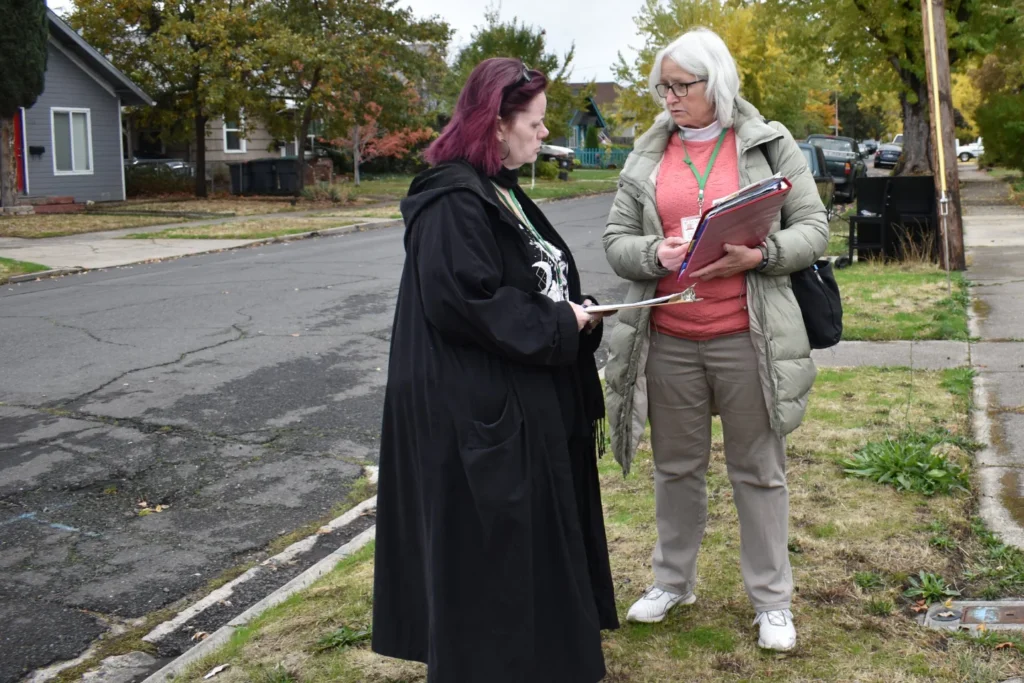 Two volunteers are talking to each other as they prepare to go door-to-door in a West Medford neighborhood
